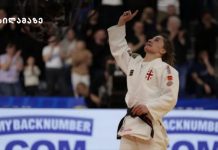 ეთერ ლიპარტელიანი ევროპის ჩემპიონია Female judo athlete in a white gi with a black belt raises her right fist in celebration on the mat, with cheering spectators in the background.
